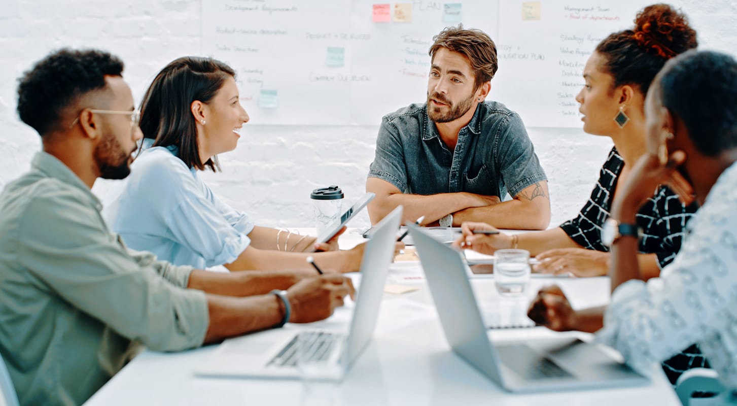 Groupe de professionnels assis à une table et engagés dans une discussion de groupe.